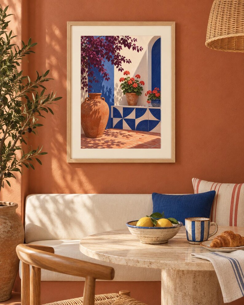 Pu&ograve; includere: Una stampa d'arte da parete incorniciata che raffigura una scena mediterranea con una grande anfora in terracotta, gerani in vaso e piastrelle geometriche blu e bianche su una parete bianca, con ombre profonde e colori vivaci sotto la luce.