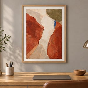 May include: A framed abstract wall art print featuring textured layers of terracotta, cream, beige, and olive green paint with a small vertical accent of bright blue, presented in a light wood frame with a white mat border.