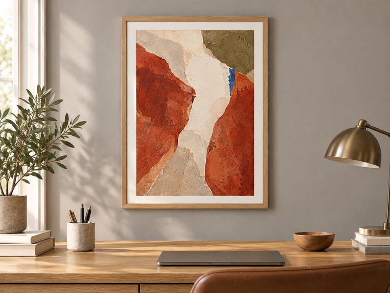 May include: A framed abstract wall art print featuring textured layers of terracotta, cream, beige, and olive green paint with a small vertical accent of bright blue, presented in a light wood frame with a white mat border.