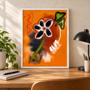 May include: A framed digital art print featuring a vibrant orange background with a central stylized flower. The flower has dark petals with white outlines, a green stem, and a red center. Abstract elements include a red zigzag line and green leaf.