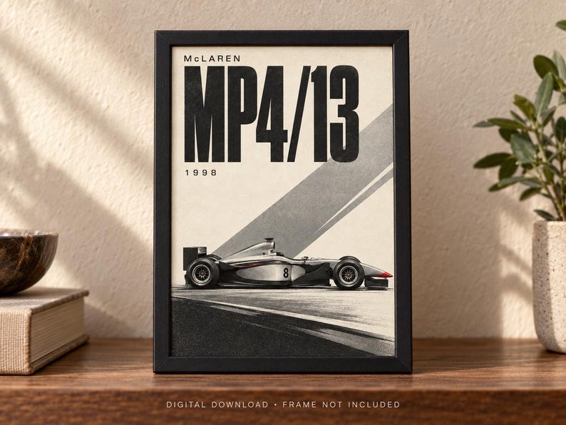 May include: A framed poster featuring a side profile of a McLaren MP4/13 Formula One race car. The design includes the text "McLAREN", "MP4/13", and "1998" in bold black lettering against a cream background with diagonal gray stripes.