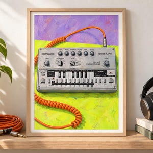 May include: A framed print featuring a silver Roland TB-303 Bass Line synthesizer with a bright orange coiled cable. The device is set against a vibrant background of purple and lime green brushstrokes, highlighting the knobs and buttons.