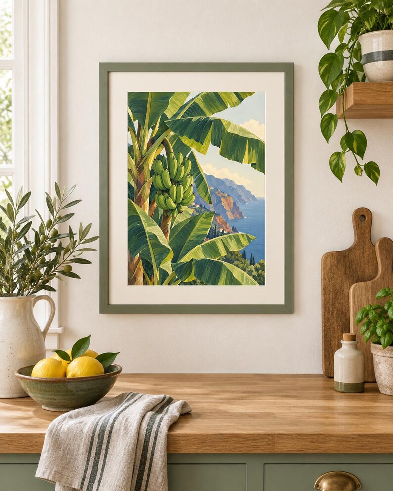 May include: A framed wall art print featuring a vibrant illustration of a banana tree with a large bunch of green bananas, set against a coastal landscape with blue water, distant cliffs, and a clear sky, enclosed in a matte olive green frame.