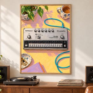Pu&ograve; includere: Una stampa artistica incorniciata che raffigura una drum machine Roland TR-606 Drumatix argentata su una superficie gialla. L'illustrazione include un cavo audio blu, una pianta in vaso, una tazza in ceramica, una ciotola e un libro viola.