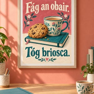 Pu&ograve; includere: Una stampa incorniciata raffigurante un libro verde acqua, un biscotto con gocce di cioccolato e una tazza a motivi floreali su sfondo rosa. Il testo recita F&aacute;g an obair. T&oacute;g briosca. L'illustrazione include piccoli fiori bianchi e un cuore rosa.