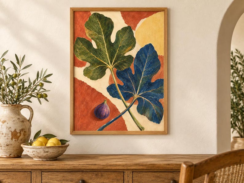 May include: A framed wall art print featuring a large green fig leaf and a large blue fig leaf overlapping on a background of abstract terracotta and cream shapes, with a single small purple fig fruit positioned in the lower left corner.