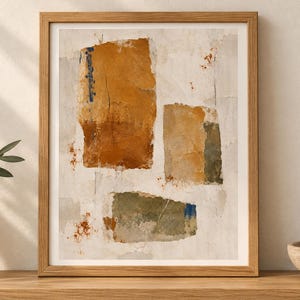 May include: A framed abstract wall art print featuring three distinct rectangular shapes in shades of ochre, burnt orange, and muted olive green against a textured off-white background with subtle blue and rust-coloured paint splatters.