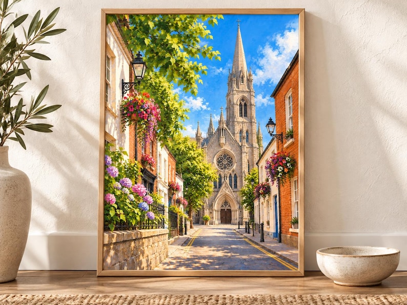 Pu&ograve; includere: Una stampa d'arte da parete incorniciata che raffigura una stretta strada europea con un'alta chiesa in pietra dotata di guglia e rosone sullo sfondo. La strada &egrave; fiancheggiata da edifici in mattoni, cesti di fiori appesi e ortensie.