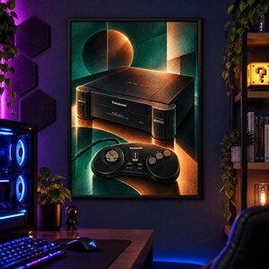 Puede incluir: Una l&aacute;mina de arte mural enmarcada que muestra una consola de juegos Panasonic Real FZ-1 3DO negra y su mando a juego, sobre un fondo oscuro y abstracto con patrones de luz circulares y geom&eacute;tricos en naranja y azul cerceta.
