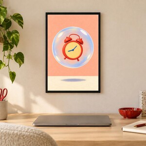 May include: A framed wall art print featuring a red analog alarm clock encased within a transparent bubble, set against a solid peach-colored background. The clock has a yellow face with blue hands and sits above a dark oval shadow on the floor.