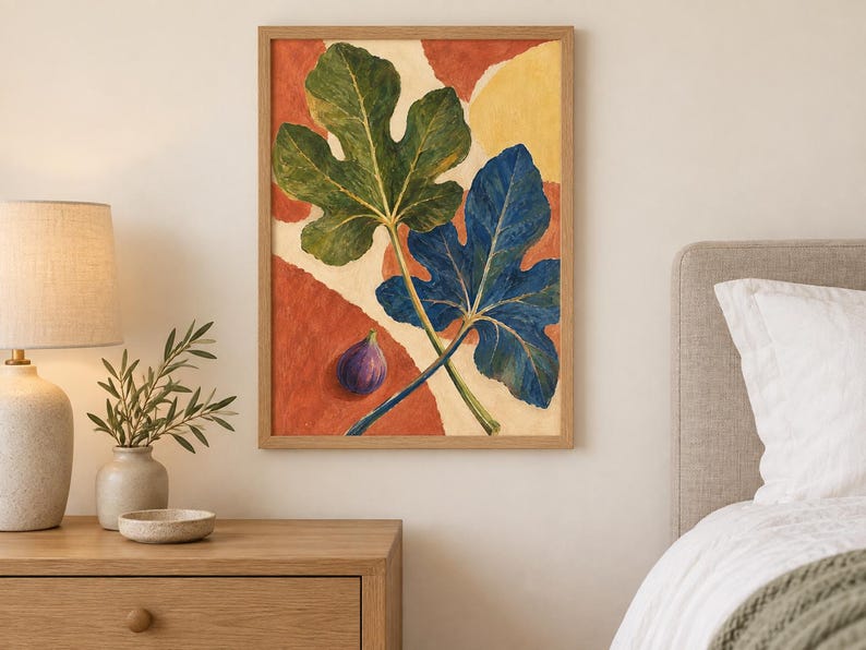 May include: A framed wall art print featuring a botanical illustration of two large fig leaves, one green and one blue, alongside a single purple fig. The background consists of abstract, rounded shapes in shades of terracotta orange and cream.