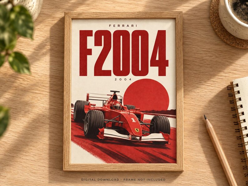 May include: A framed poster featuring a red Ferrari F2004 Formula 1 race car on a track. The text FERRARI F2004 and 2004 appears at the top. A large red circle is positioned behind the car. The poster is displayed in a light wood frame.
