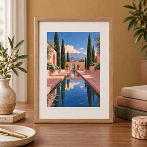 Pu&ograve; includere: Una stampa artistica incorniciata raffigurante un paesaggio mediterraneo con una lunga piscina riflettente rettangolare, alti cipressi, pareti in stucco rosa e montagne in lontananza sotto un cielo azzurro, in una cornice di legno chiaro.