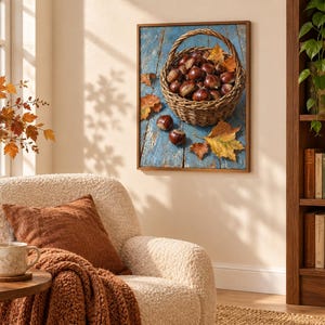 May include: A framed wall art print depicting a woven basket filled with brown chestnuts and scattered autumn leaves resting on a weathered blue wooden surface. The artwork features a rustic harvest theme with warm orange and yellow foliage tones.