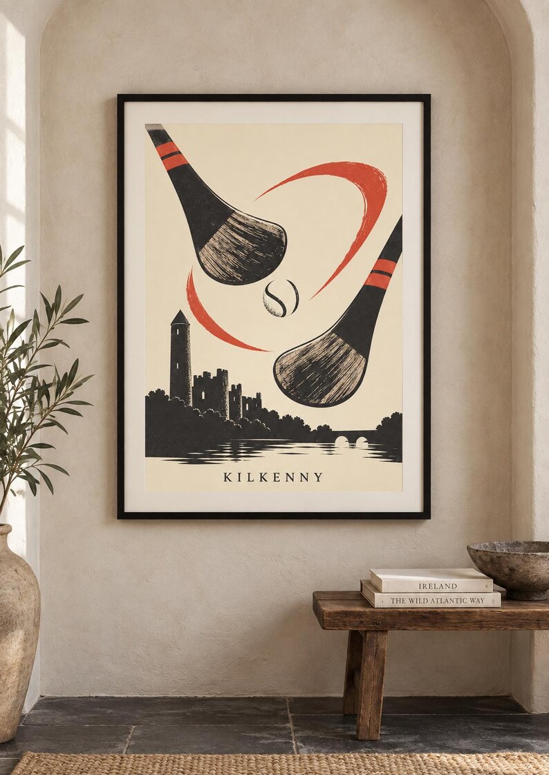 Peut inclure: Une affiche encadr&eacute;e pr&eacute;sentant une illustration stylis&eacute;e de deux crosses de hurling noires et rouges frappant une balle au-dessus d'une silhouette noire du ch&acirc;teau de Kilkenny et d'une rivi&egrave;re. Le mot KILKENNY est inscrit en bas.