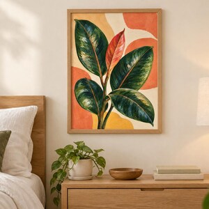 May include: A framed wall art print featuring a botanical illustration of a rubber plant with deep green leaves and one central reddish leaf, set against an abstract background of soft orange and yellow shapes in a light wood frame.