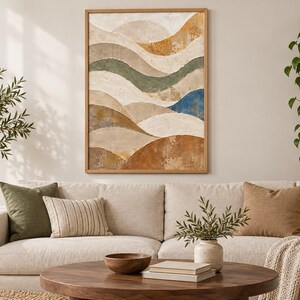 Pu&ograve; includere: Un'opera d'arte murale rettangolare incorniciata che presenta un paesaggio astratto di onde stratificate e strutturate nei toni del crema, beige, ocra, verde salvia e un accento blu scuro, racchiusa in una semplice cornice in legno chiaro.