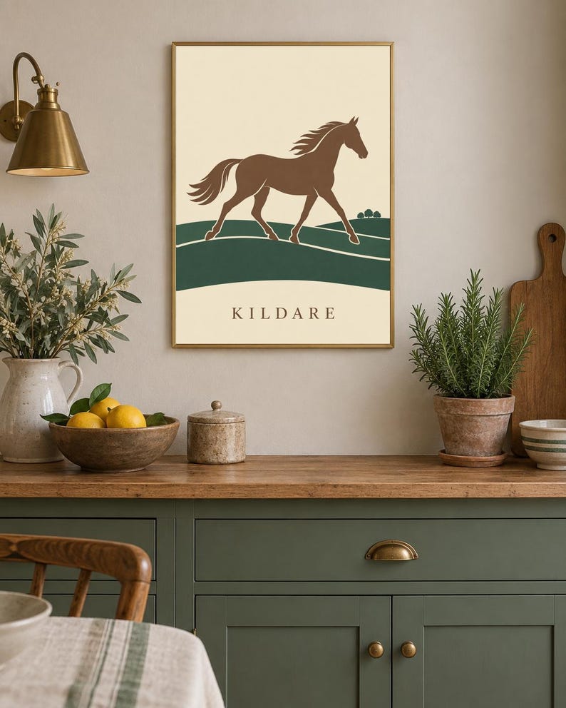 May include: A rectangular wall art print in a thin gold frame featuring a brown horse galloping across a dark green landscape against a cream background. The word KILDARE is printed in dark brown capital letters at the bottom of the print.
