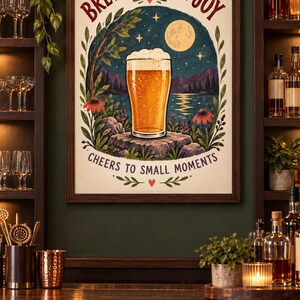 May include: A framed wall art print featuring a glass of beer on a rock by a lake under a full moon. The text reads BREW A LITTLE JOY and CHEERS TO SMALL MOMENTS. The illustration includes flowers, trees, and mountains in a dark, natural color palette.
