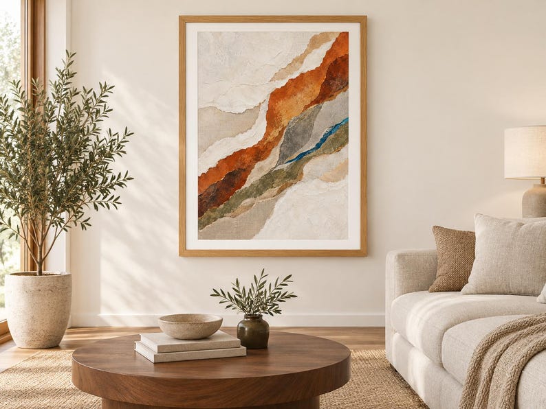 May include: A framed abstract wall art piece featuring layered, torn-paper style textures in shades of burnt orange, deep brown, muted green, and cream. The composition displays diagonal, organic bands of color with a thin, vibrant blue accent line.