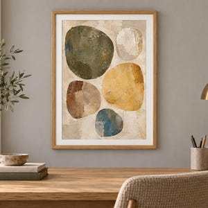 May include: A framed wall art print featuring an abstract composition of five large, rounded organic shapes in shades of olive green, mustard yellow, brown, blue, and off-white, set against a textured, neutral-toned background within a light wood frame.