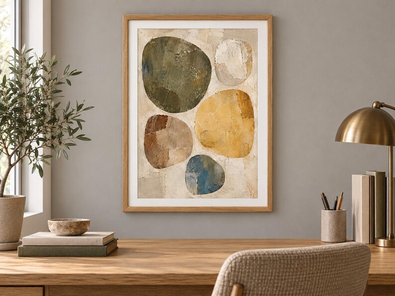 May include: A framed wall art print featuring an abstract composition of five large, rounded organic shapes in shades of olive green, mustard yellow, brown, blue, and off-white, set against a textured, neutral-toned background within a light wood frame.
