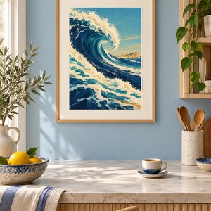 May include: A framed art print featuring a large, curling ocean wave in shades of deep blue, turquoise, and white, with a distant coastline visible under a clear sky. The artwork is enclosed in a light-toned wooden frame with a white mat border.