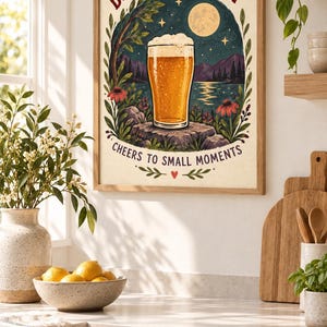 May include: A framed wall art print featuring a glass of golden beer on a rock, surrounded by flowers and a night landscape with a full moon. The text reads BREW A LITTLE JOY at the top and CHEERS TO SMALL MOMENTS at the bottom in dark red and black.