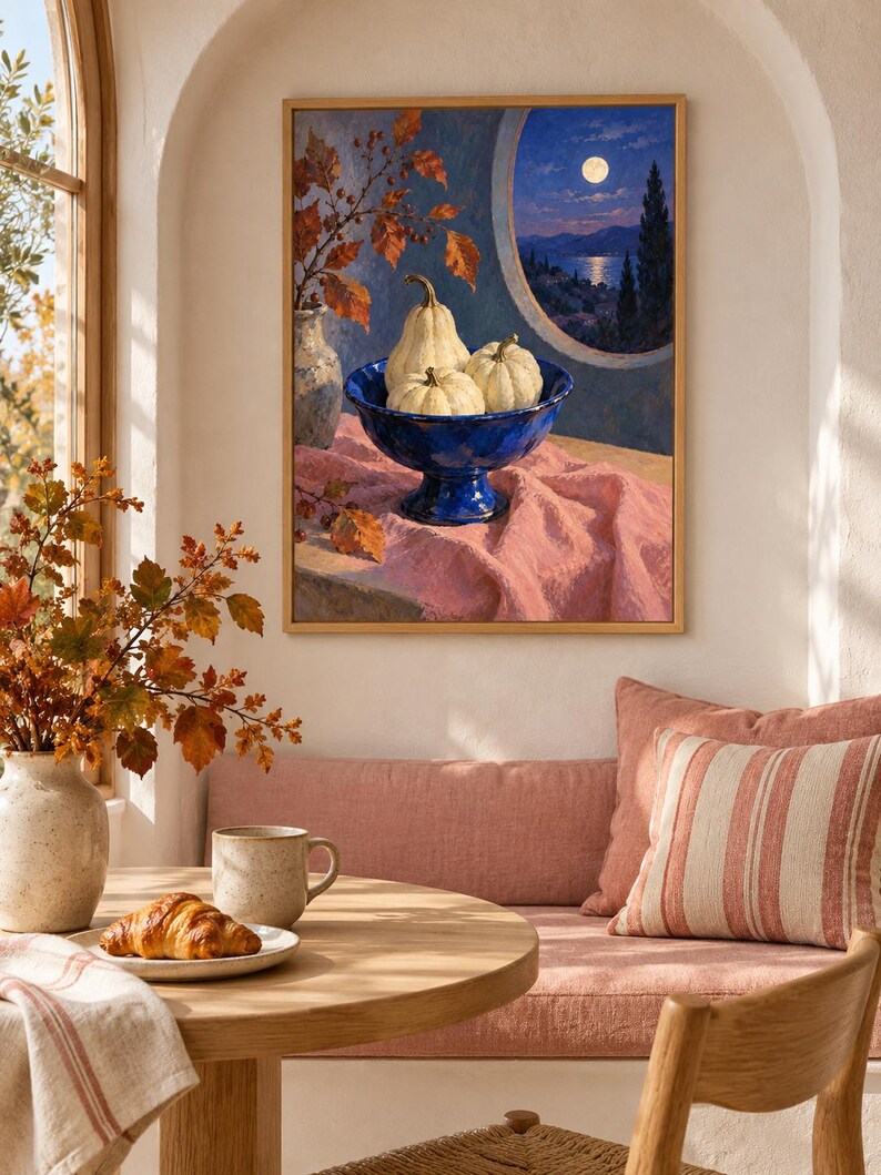 May include: A framed wall art print depicting a still life scene with three white pumpkins in a deep blue pedestal bowl, resting on a pink cloth. The background shows a moonlit coastal landscape viewed through a circular window frame.
