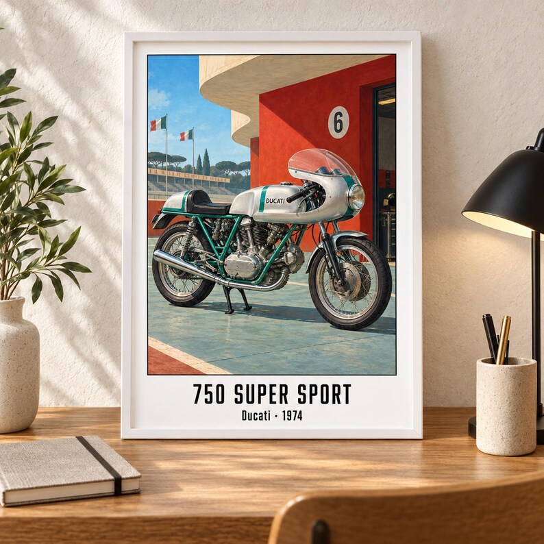 Puede incluir: Una l&aacute;mina de arte enmarcada que muestra una motocicleta Ducati 750 Super Sport de 1974 en color plata y verde, aparcada frente a un edificio rojo con un cartel del n&uacute;mero 6. El texto inferior dice 750 SUPER SPORT y Ducati 1974 en negro.