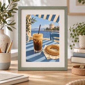 May include: A framed art print depicting a seaside scene with a glass of iced coffee and a sesame bagel on a blue table. In the background, a coastal city skyline features a prominent white cylindrical tower under a clear blue sky.