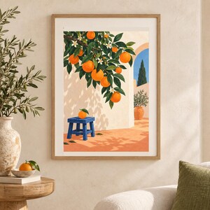 May include: A framed art print depicting a Mediterranean scene with an orange tree branch laden with bright orange fruit and white blossoms hanging over a blue wooden stool, set against a light-colored wall with a terracotta patio and blue sky.