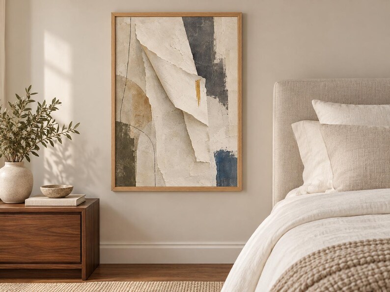 May include: A rectangular wall art piece in a light wood frame featuring an abstract composition of layered, torn-paper textures in shades of cream, beige, charcoal gray, and deep blue, accented by a single vertical gold brushstroke mark.