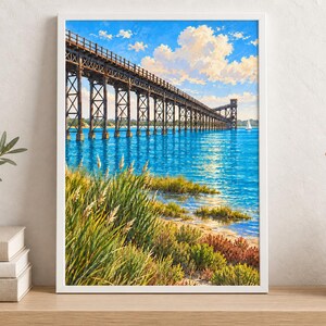 Peut inclure: Une impression d'art encadr&eacute;e repr&eacute;sentant un long pont &agrave; chevalets en bois s'&eacute;tendant au-dessus d'une eau bleu vif. Le premier plan pr&eacute;sente des herbes c&ocirc;ti&egrave;res vertes et des arbustes bas sous un ciel bleu vif avec des nuages blancs.