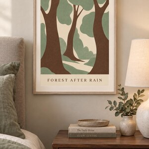 May include: A framed wall art print titled FOREST AFTER RAIN featuring a stylized illustration of trees with brown trunks and sage green foliage against a cream background. The artwork is displayed in a light wood frame with a clean, simple border.