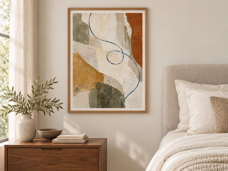 Puede incluir: Una impresi&oacute;n de arte mural abstracto enmarcada que presenta formas org&aacute;nicas en capas en tonos crema, terracota, amarillo mostaza y verde oliva. Una l&iacute;nea &uacute;nica, fina y de color azul oscuro se curva y forma un bucle en el centro de la composici&oacute;n, contrastando con los bloques de colores terrosos y texturizados.