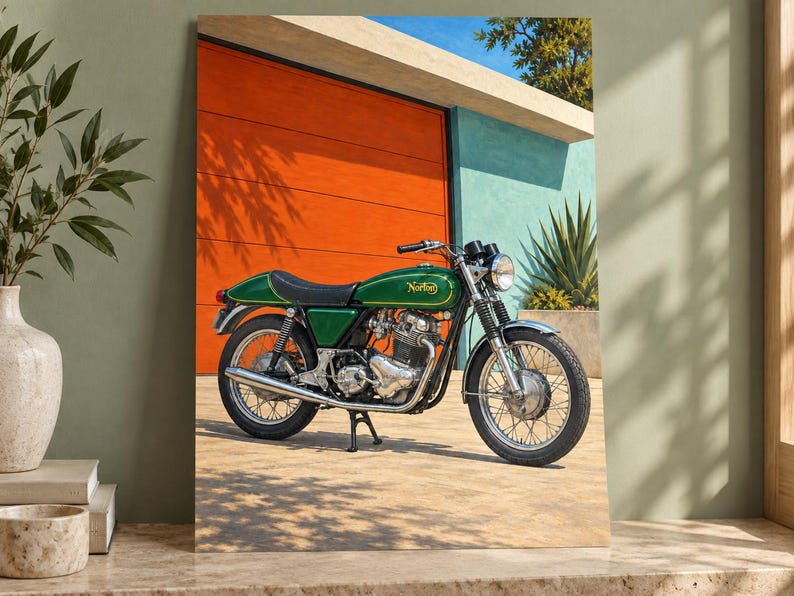 May include: A green Norton motorcycle with a black seat, chrome exhaust, and wire-spoke wheels parked on a paved surface. The motorcycle features a classic fuel tank design with gold lettering and is positioned in front of a bright orange wall.