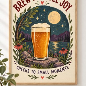May include: A framed wall art print featuring a glass of golden beer with foam on a rock, set against a night landscape with a full moon, mountains, and lake. The text reads BREW A LITTLE JOY at the top and CHEERS TO SMALL MOMENTS at the bottom.