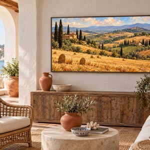 May include: A rectangular wall-mounted television displaying a landscape painting of a golden wheat field with hay bales, cypress trees, and stone villas under a blue sky with clouds, positioned above a long wooden media console cabinet.