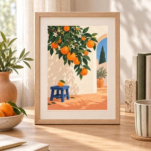 May include: A framed art print featuring a painting of an orange tree branch with bright orange fruit and green leaves hanging over a blue stool with a single orange on top, set against a light-colored wall with a blue sky and archway.