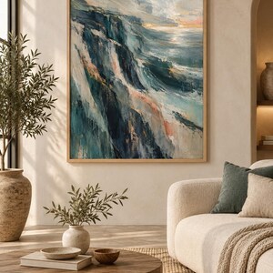 May include: A framed rectangular wall art piece featuring an abstract coastal landscape painting with deep navy, teal, and soft peach brushstrokes. The artwork depicts a rugged cliffside meeting the ocean under a light sky, encased in a light wood frame.