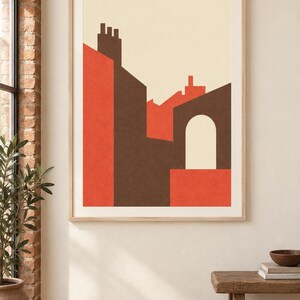 K&ouml;nnte beinhalten: Ein gerahmter Wandkunstdruck mit einer geometrischen architektonischen Komposition. Das Design zeigt flache Formen in Dunkelbraun, leuchtendem Orange und Creme, die stilisierte Geb&auml;udesilhouetten mit einem zentralen Torbogen darstellen.