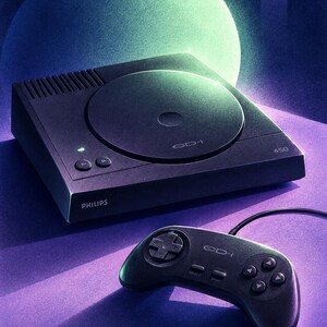 K&ouml;nnte beinhalten: Eine schwarze Philips CD-i 450 Spielkonsole mit kreisf&ouml;rmigem Disc-Deckel, einer Betriebsanzeige und zwei Tasten auf der Oberseite. Ein passender schwarzer kabelgebundener Controller mit Steuerkreuz, Select- und Start-Tasten sowie vier Aktionstasten.