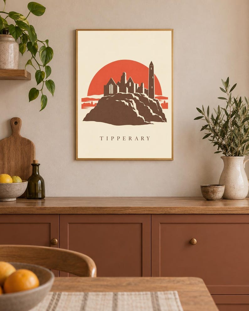 May include: A rectangular wall art print featuring a stylized illustration of the Rock of Cashel in Tipperary, Ireland. The design displays a dark brown castle silhouette against a large red sun, set on a cream background with the text TIPPERARY.
