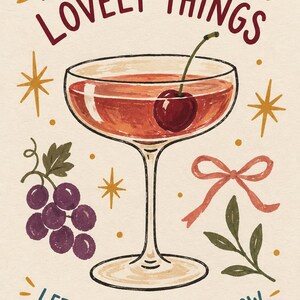 May include: A cream-colored print featuring a cocktail glass filled with a reddish liquid and a cherry. Text reads A TOAST TO THE LOVELY THINGS and LET THE GOOD TIMES GLOW. Illustrations include purple grapes, a pink ribbon, and gold starbursts.