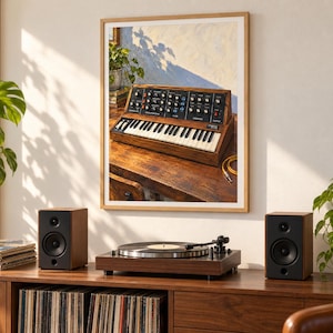 May include: A framed wall art print depicting a vintage analogue synthesiser with a wooden casing, black control panel, and white and black keys. The synthesiser is positioned on a wooden desk, featuring various knobs, switches, and a patch cable.