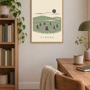 May include: A framed rectangular wall art print featuring a stylized landscape illustration of a stone circle in a green field under a dark sun, with the text TYRONE printed in black capital letters at the bottom center of the cream background.