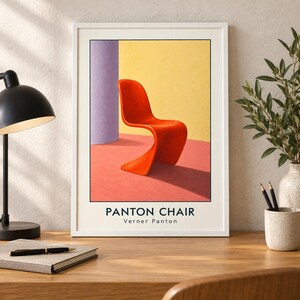 May include: A framed art print featuring a vibrant orange S-shaped chair centered against a yellow wall and a purple pillar on a pink floor. The text PANTON CHAIR and Verner Panton is printed in black at the bottom of the white-bordered poster.