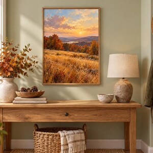 May include: A framed landscape painting depicting a golden autumn sunset over rolling hills and a distant river. The scene features tall, dry grasses in the foreground, vibrant orange and red trees, and a soft, glowing sky with scattered clouds.