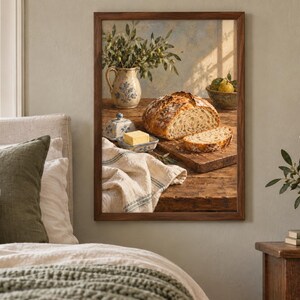 Peut inclure: Une impression d'art murale encadr&eacute;e repr&eacute;sentant une nature morte rustique sur une table en bois. L'image montre une miche de pain au levain tranch&eacute;e, une noisette de beurre jaune dans un plat en c&eacute;ramique, un pichet avec des brins verts et un bol de poires.